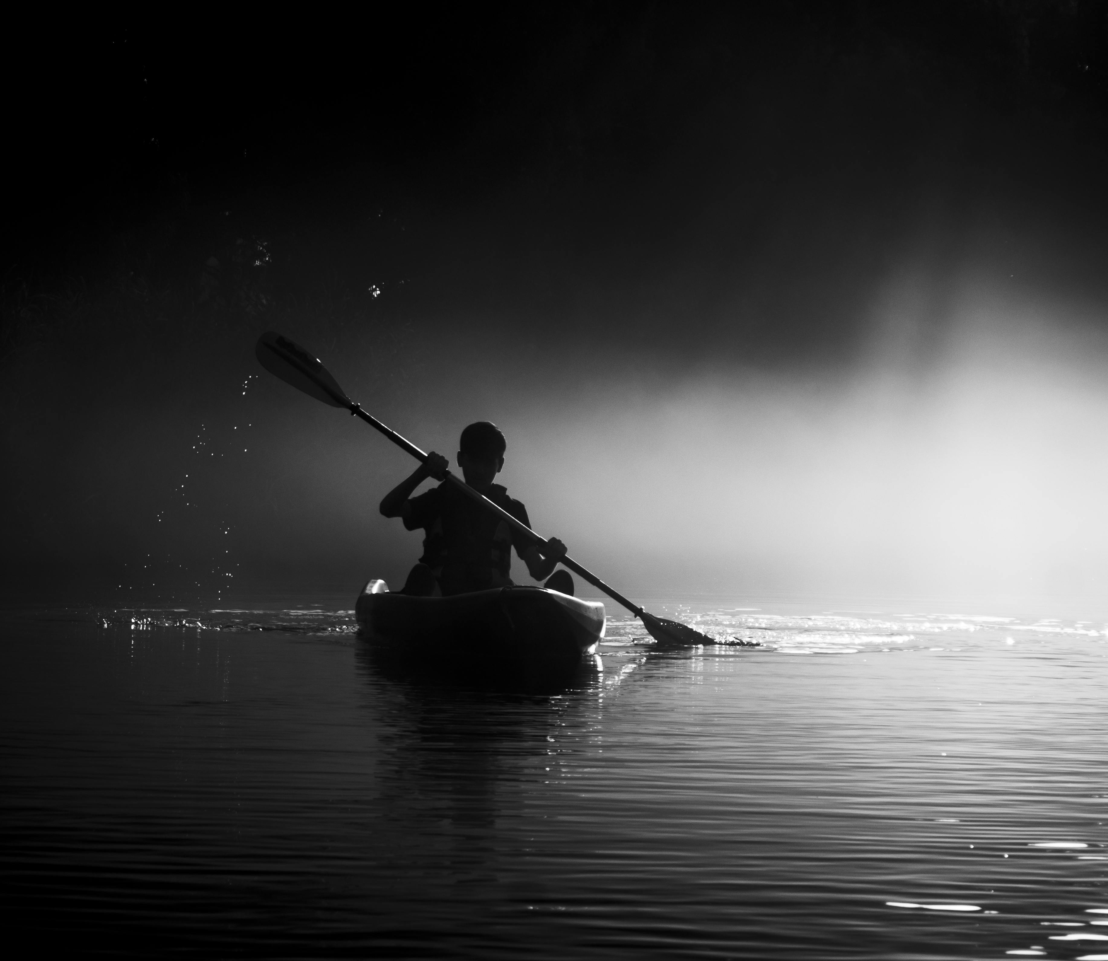 Paddle at dawn or dusk. kayaker in black and white